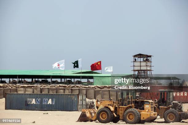 Wan Hai Line Ltd. Shipping container sits beyond an excavator outside a workers camp, operated by China Overseas Ports Holding Co., in Gwadar,...