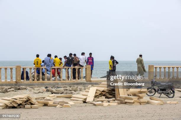 People gather next to construction materials for a sidewalk on Marine Drive in Gwadar, Balochistan, Pakistan, on Tuesday, July 4, 2018. What used to...