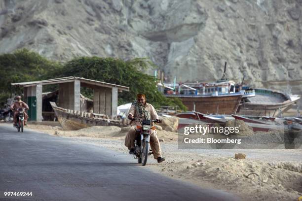 Motorcyclists ride along a road past fishing boats on Marine Drive, in Gwadar, Balochistan, Pakistan, on Tuesday, July 4, 2018. What used to be a...