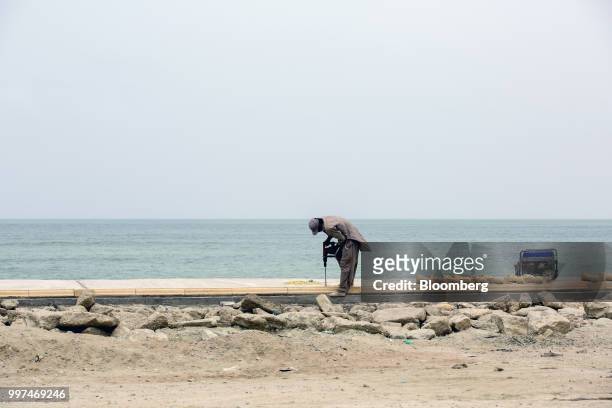 Construction worker drills a hole in a sidewalk on Marine Drive in Gwadar, Balochistan, Pakistan, on Tuesday, July 4, 2018. What used to be a small...