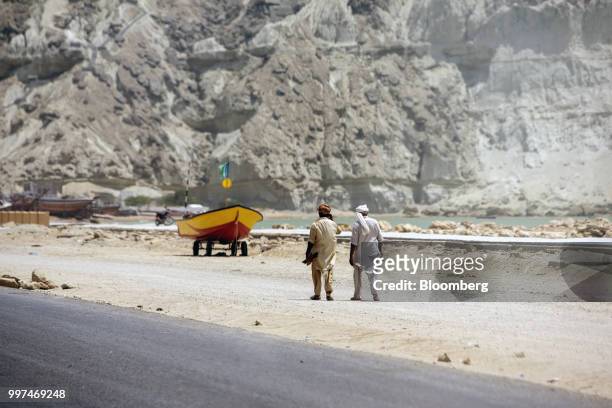 Workers walk along a road on Marine Drive in Gwadar, Balochistan, Pakistan, on Tuesday, July 4, 2018. What used to be a small fishing town on the...