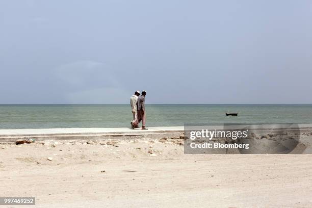 Workers walk along a sidewalk on Marine Drive in Gwadar, Balochistan, Pakistan, on Tuesday, July 4, 2018. What used to be a small fishing town on the...