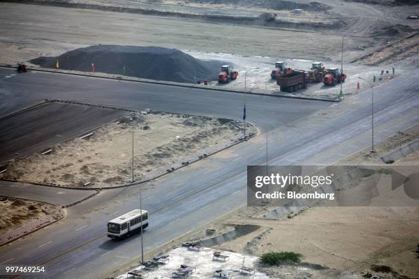 Bus travels along a road past a development site, operated by China Overseas Ports Holding Co., near Gwadar Port in Gwadar, Balochistan, Pakistan, on...