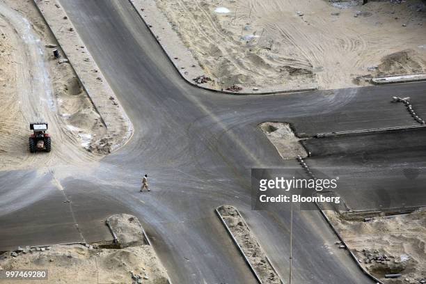 Man crosses a road next to a development site, operated by China Overseas Ports Holding Co., near Gwadar Port in Gwadar, Balochistan, Pakistan, on...