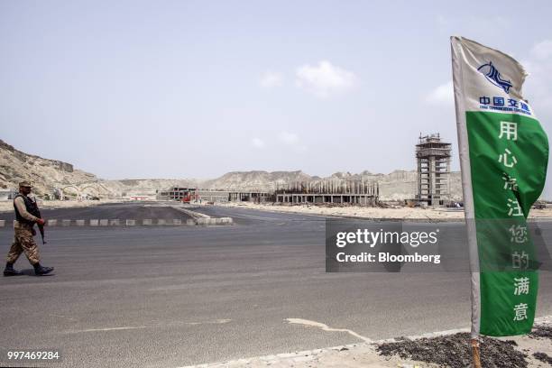 Member of the security forces walks through a development site, operated by China Overseas Ports Holding Co., near Gwadar Port in Gwadar,...