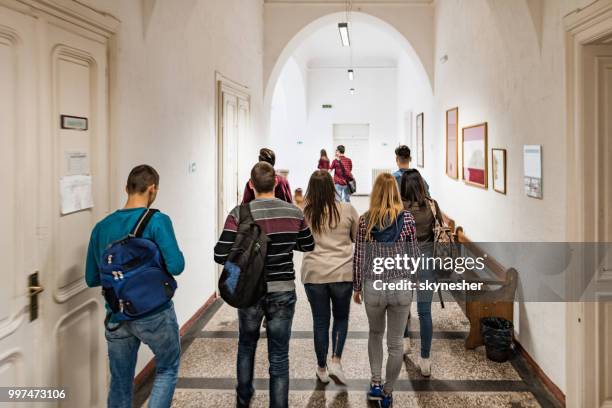 achteraanzicht van een grote groep studenten lopen in de lobby van de school. - corridor stockfoto's en -beelden