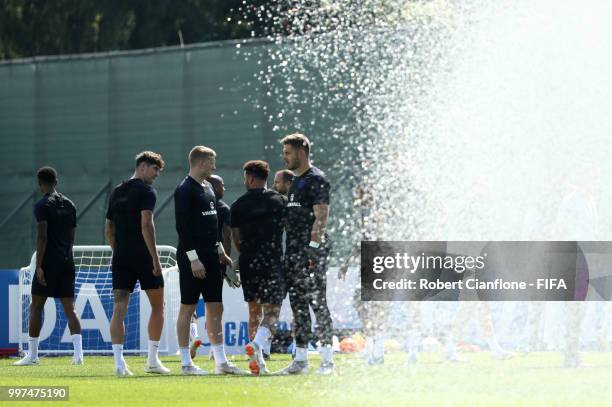 Players take part in a drill as the sprinklers spray water during an England training session during the 2018 FIFA World Cup Russia at Spartak...