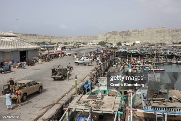 Members of the security forces stand near fishing boats at the harbor in Gwadar, Balochistan, Pakistan, on Tuesday, July 4, 2018. What used to be a...