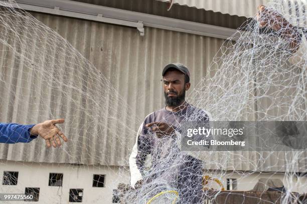 Men tend to a fishing net at the harbor in Gwadar, Balochistan, Pakistan, on Tuesday, July 4, 2018. What used to be a small fishing town on the...