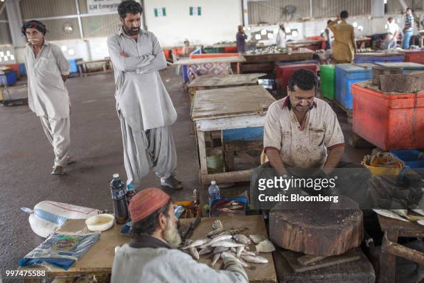 Fishmonger scales a fish in a market at the harbor in Gwadar, Balochistan, Pakistan, on Tuesday, July 4, 2018. What used to be a small fishing town...