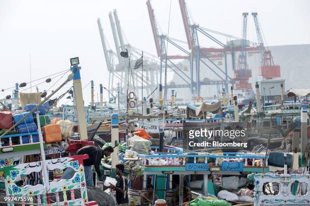 Fishing boats sit moored at the harbor as gantry cranes stand in the background at Gwadar Port in Gwadar, Balochistan, Pakistan, on Tuesday, July 4,...