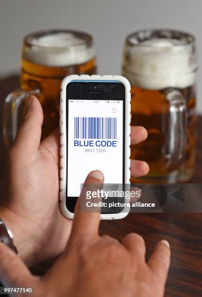 Man holding his phone running the new Oktoberfest payment app "Blue Code", in front of two beers, after a press conference for this year's...