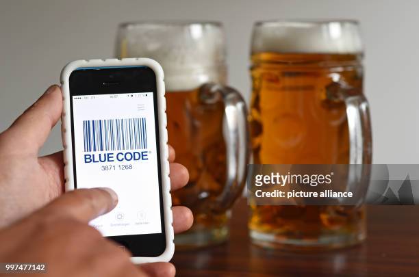 Man holding his phone running the new Oktoberfest payment app "Blue Code", in front of two beers, after a press conference for this year's...