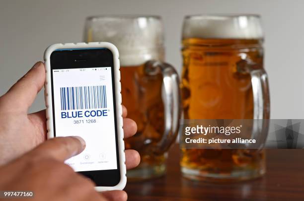 Dpatop - ILLUSTRATION - A man holding his phone running the new Oktoberfest payment app "Blue Code", in front of two beers, after a press conference...