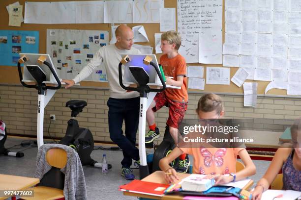 Class teacher Stefan Megerle talks to a year five pupil who is attending a German class while sitting on a bicycle at the...