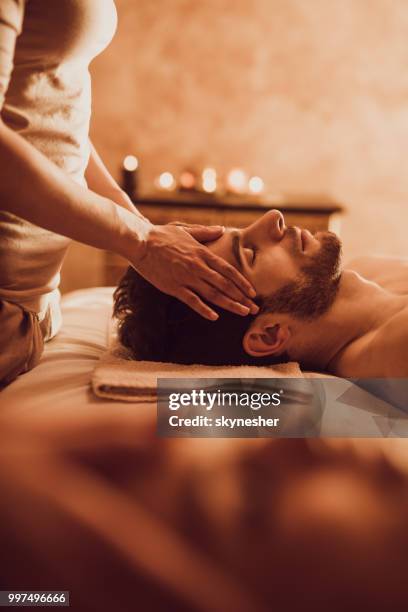 hombre joven tener relajante masaje en el spa. - head massage fotografías e imágenes de stock