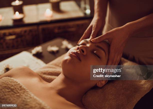 serena donna afroamericana che riceve un massaggio alla testa presso la beauty spa. - massaggio del viso foto e immagini stock