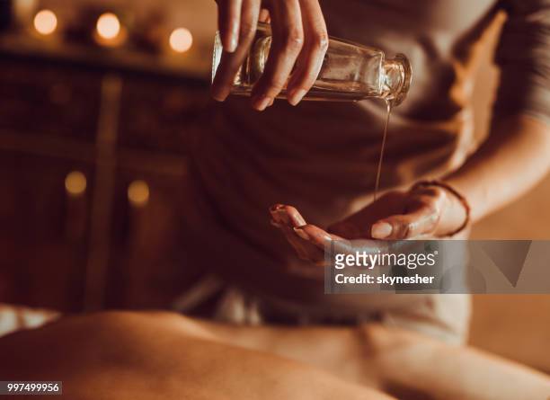 nahaufnahme von unkenntlich therapeut gießen massageöl in die hand. - skynesher stock-fotos und bilder