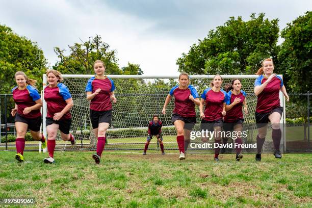 women soccer players running and kicking a ball - david freund stock pictures, royalty-free photos & images