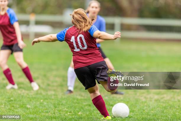 women soccer players running and kicking a ball - david freund stock pictures, royalty-free photos & images