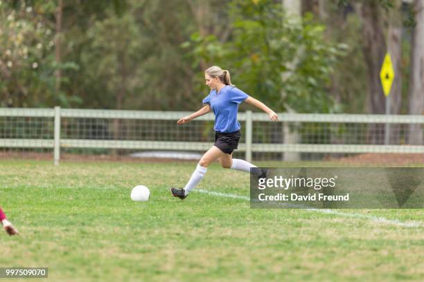 women soccer players running and kicking a ball - david freund stockfoto's en -beelden