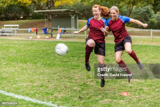 women soccer players running and kicking a ball - david freund stock pictures, royalty-free photos & images