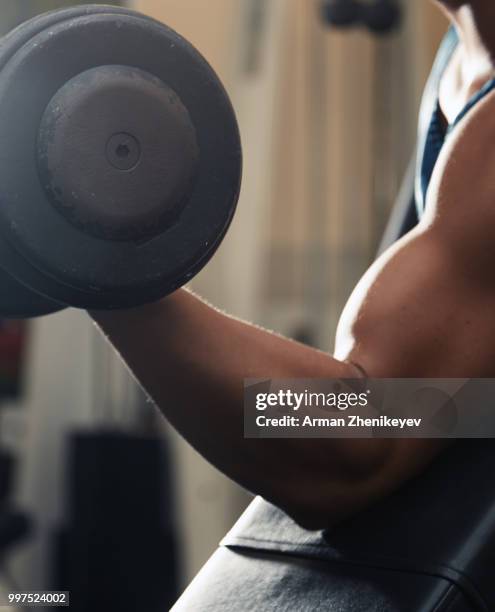 muscular man lifting dumbbell - arman zhenikeyev photos et images de collection