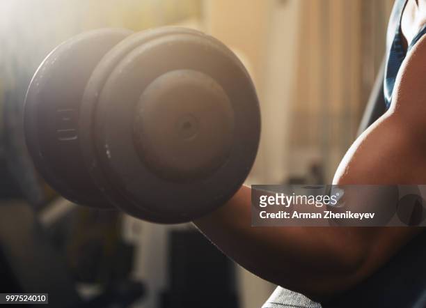 muscular man lifting dumbbell - arman zhenikeyev stock-fotos und bilder