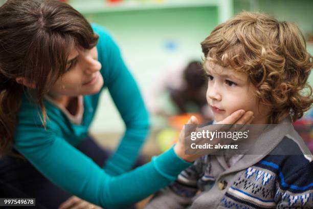 teacher comforting upset boy in classroom - teacher crying stock pictures, royalty-free photos & images