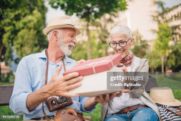mature man holding present for his wife - open marriage stock pictures, royalty-free photos & images