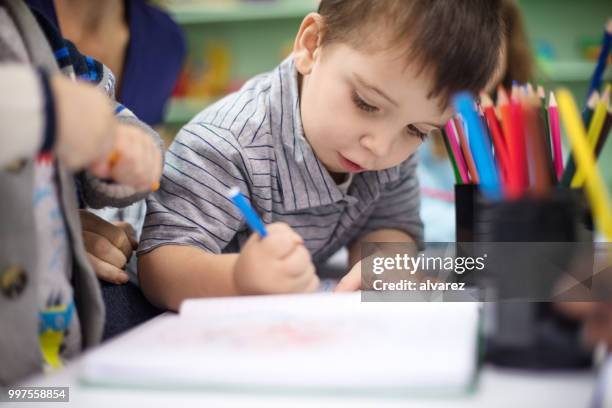 adorable boy drawing with color pencil at playschool - 3 year old stock pictures, royalty-free photos & images