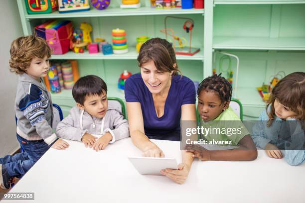 preschool leraar vertellen verhaal met digitale tablet - child care worker stockfoto's en -beelden