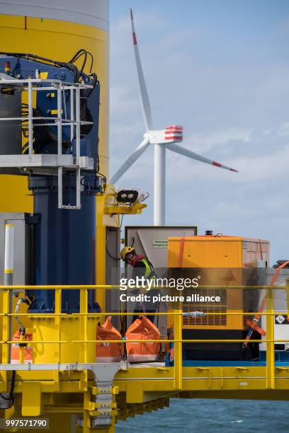 Technician can be seen moving material on the lower work platform of a wind turbine at the offshore wind park "Nordsee 1" in front of the East...