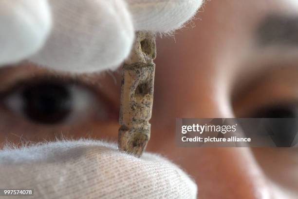Archaeologist Sybille Wolf inspects a 40,000 year old bead made of ivory, which can be seen in a exhibition case at the Prehistoric museum in...
