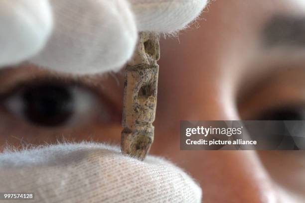 Dpatop - Archaeologist Sybille Wolf inspects a 40,000 year old bead made of ivory, which can be seen in a exhibition case at the Prehistoric museum...