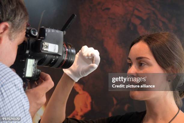 Archaeologist Sybille Wolf inspects a 40,000 year old bead made of ivory, which can be seen in a exhibition case at the Prehistoric museum in...