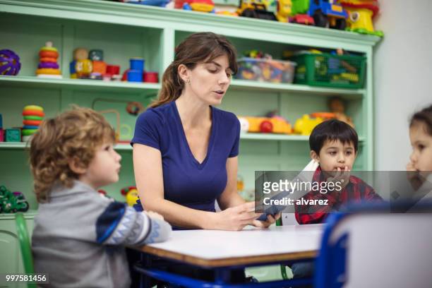 teacher reading a book to small kids in preschool. - narrating stock pictures, royalty-free photos & images