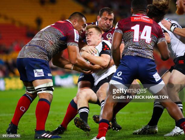 Sunwolves player Hayden Parker is tackled by Reds players Caleb Timu and JP Smith during the Super Rugby match between Australia's Queensland Reds...