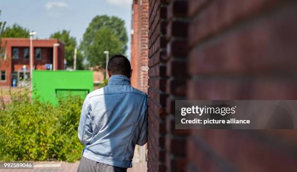 July 2018, Netherlands, Ter Apel: A refugee standing next to a wall at the central reception centre for asylum seekers 'VluchtelingenWerk...