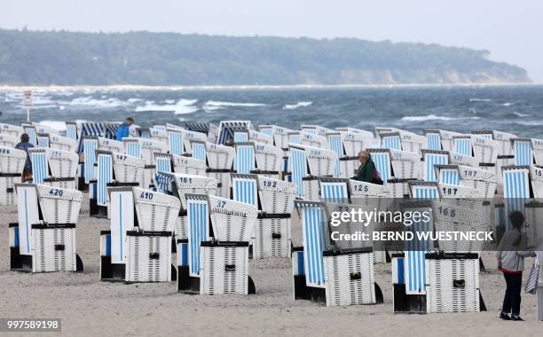 Few tourists are seen strolling around empty beach chairs on a beach in Warnemuende, at the Baltic Sea, on July 13 as the weather situation brought...