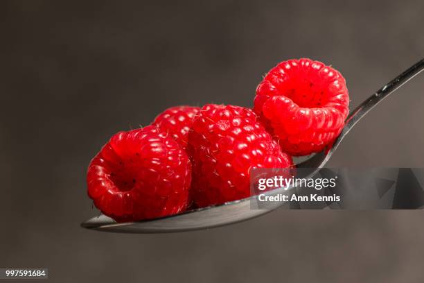 red raspberries on spoon - kennis fotografías e imágenes de stock