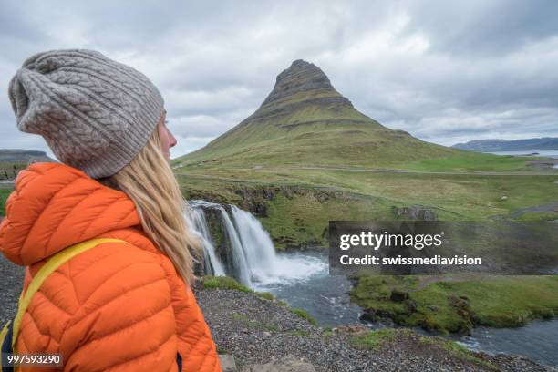 junge frau in island betrachten berühmten berg kirkjufell und wasserfälle - swissmediavision stock-fotos und bilder