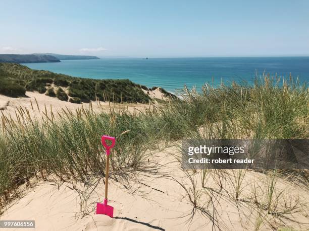 pink child’s spade in sand dunes overlooking beach - e reader - fotografias e filmes do acervo