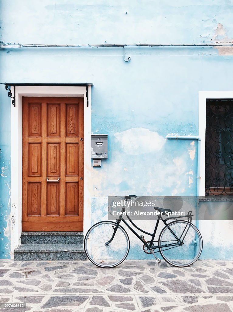 Bicycle parked against blue wall in a village