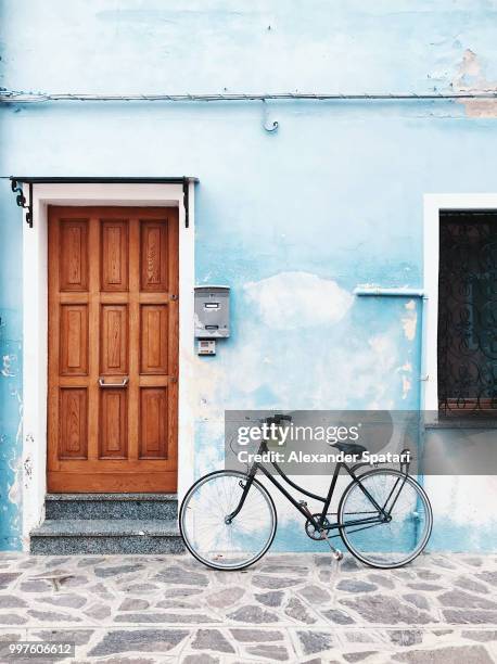 bicycle parked against blue wall in a village - amsterdam cycling stock pictures, royalty-free photos & images