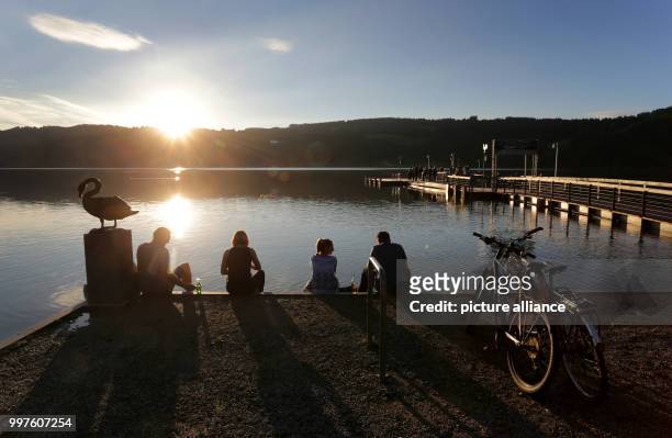 Group enjoys the sunset on the banks of a lake near Immenstadt, Germany, 28 July 2017. Photo: Karl-Josef Hildenbrand/dpa