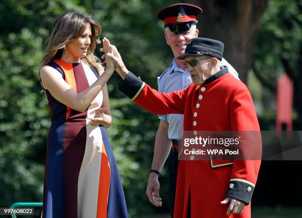 First Lady Melania Trump high-fives with a British military veteran known as a "Chelsea Pensioner" during a game of bowls at Royal Hospital Chelsea...