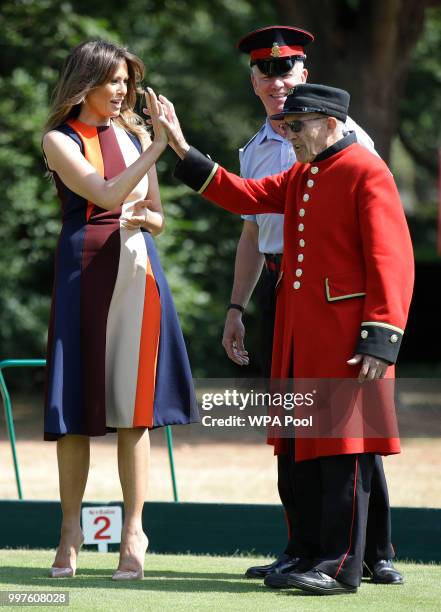 First Lady Melania Trump high-fives with a British military veteran known as a "Chelsea Pensioner" during a game of bowls at Royal Hospital Chelsea...