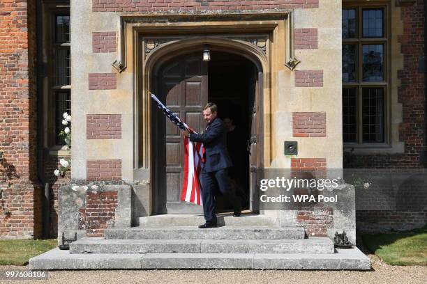 An official carries a US flag from the front door of the Prime Minister Theresa May's country residence Chequers, ahead of her talks with the US...