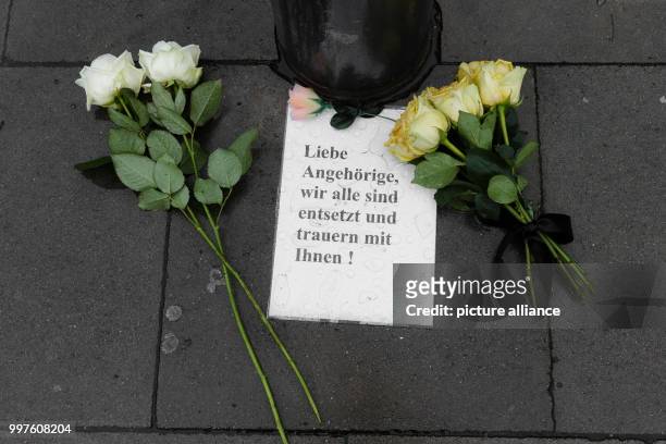 Roses and an opened letter saying 'Liebe Angehoerige, wir alle sind entsetzt und trauern mit Ihnen!' lie on the pavement in front of the supermarket...